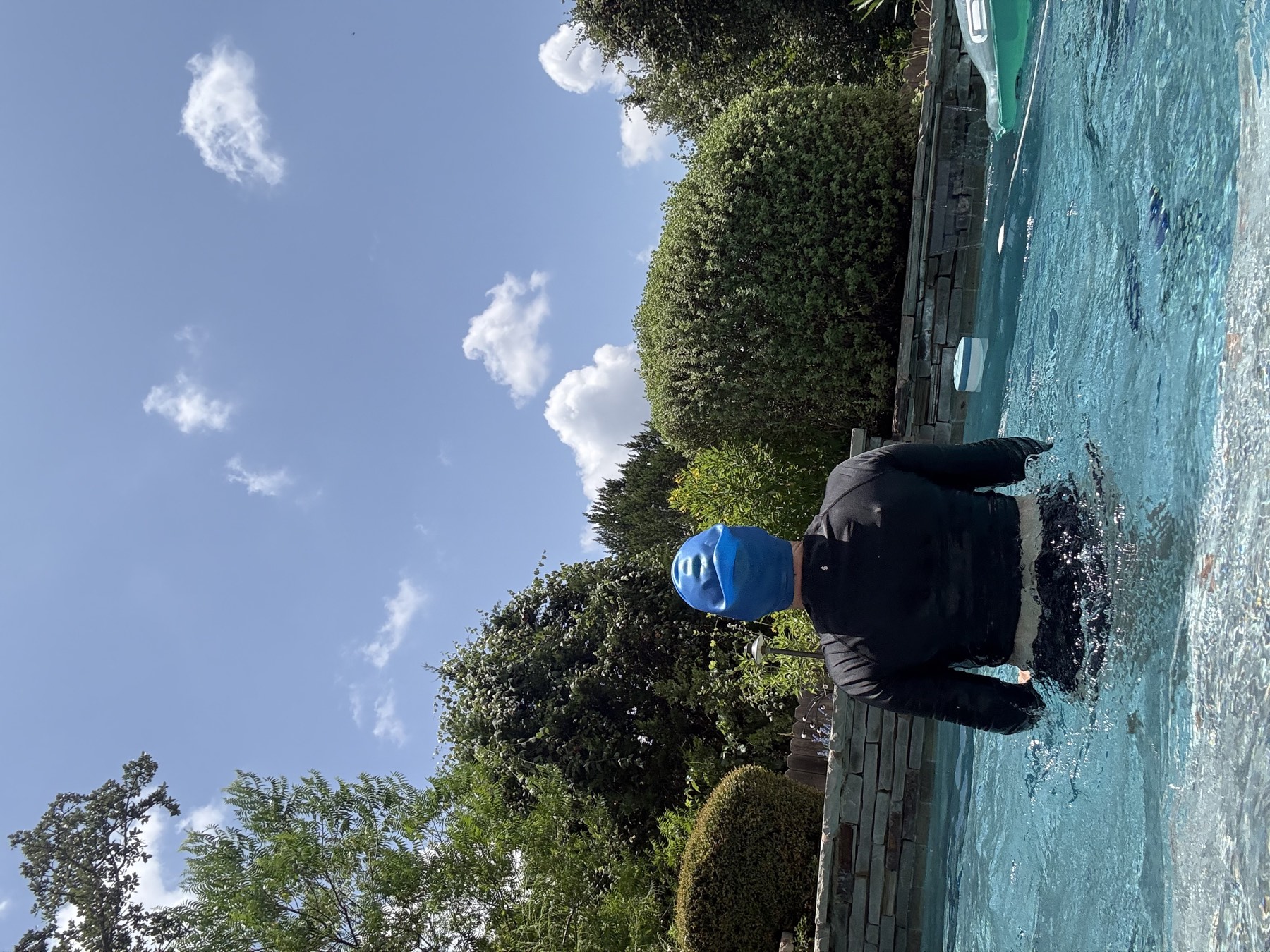 A swimmer wearing a blue swim cap in the pool, protecting color-treated hair from chlorine.