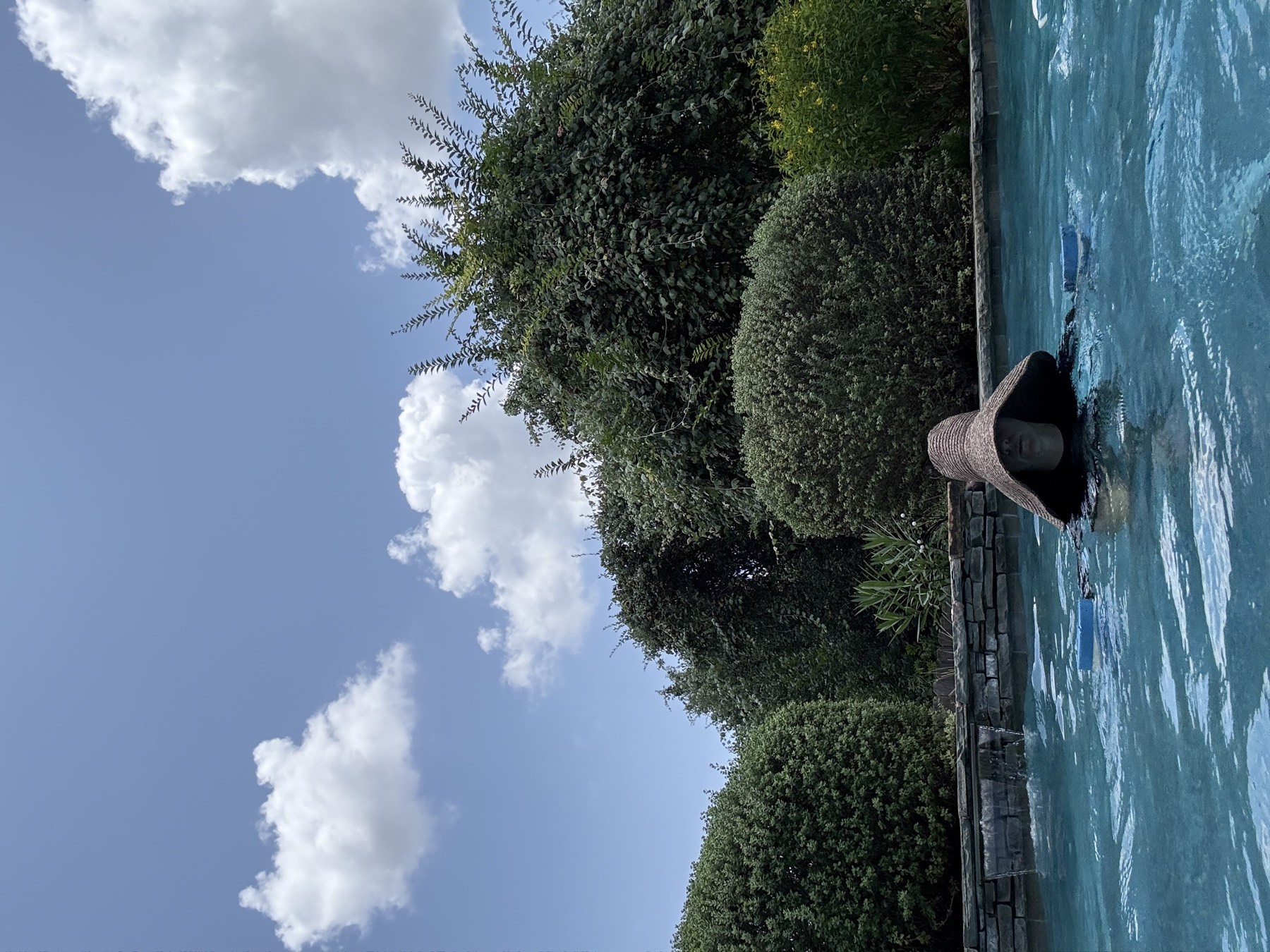 Me working in the pool in a big sun hat and long-sleeve swim top, mid-movement.