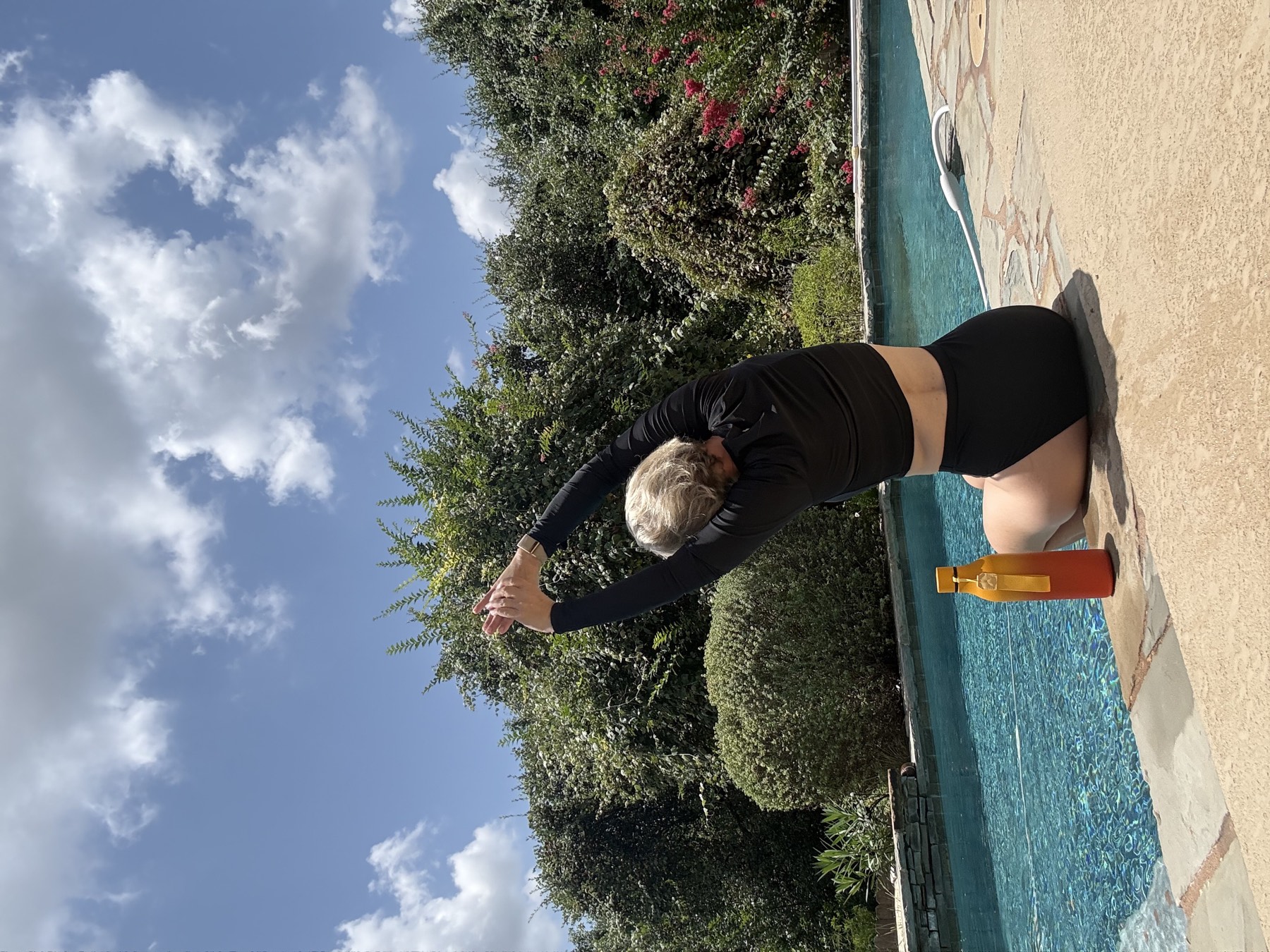 Me doing a kneeling side stretch on a mat next to the pool.