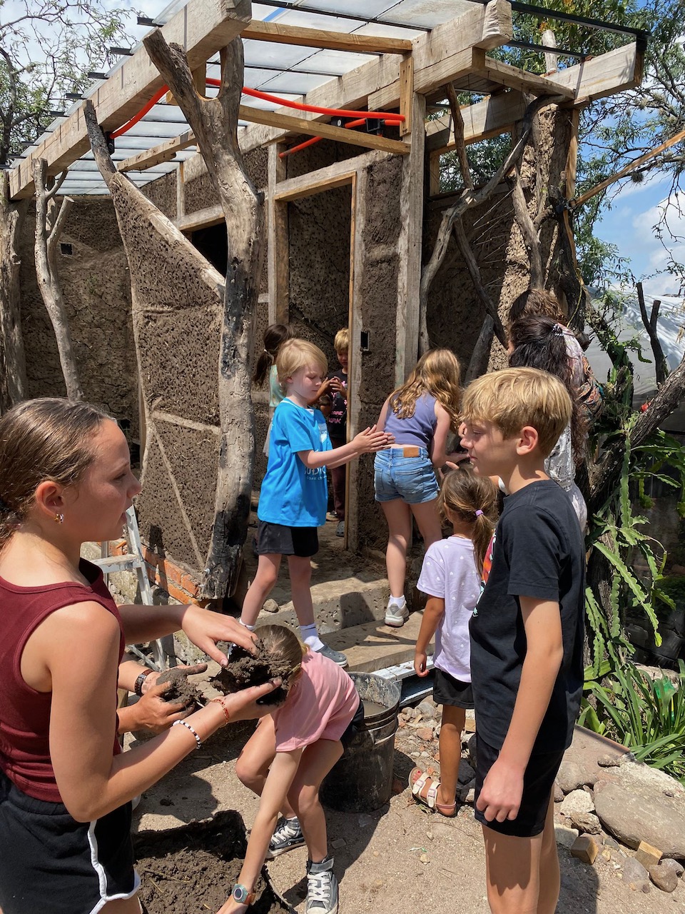 My son at camp learning to build a structure from mud, grass, and gravel