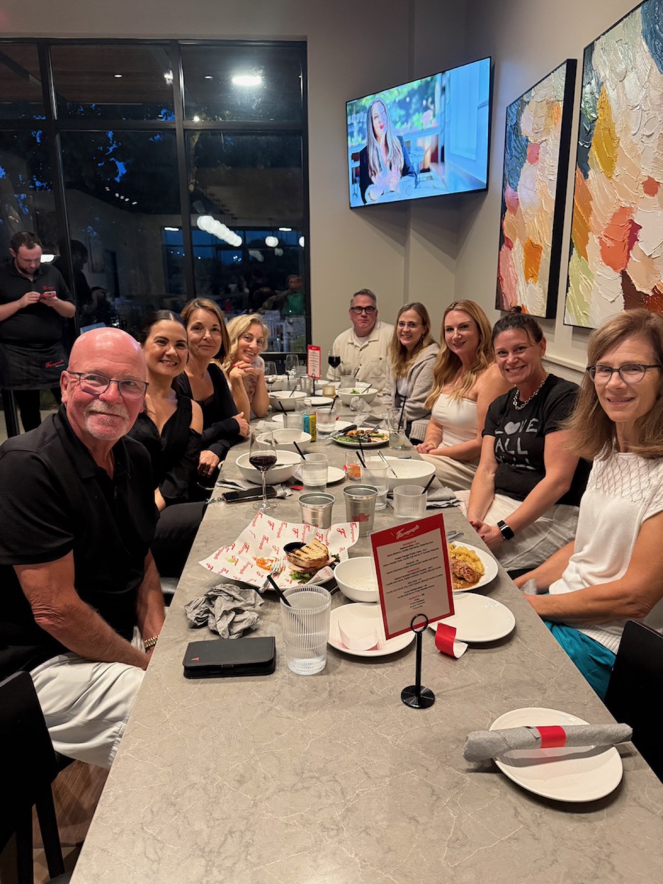A long table of neighbors smiling at the camera over dinner at the first Dinner Club.