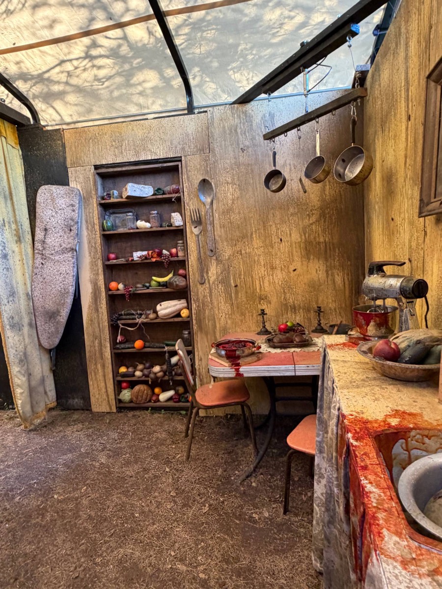 A blood-spattered vintage kitchen inside the haunt, with a fully stocked pantry shelf and hanging pots
