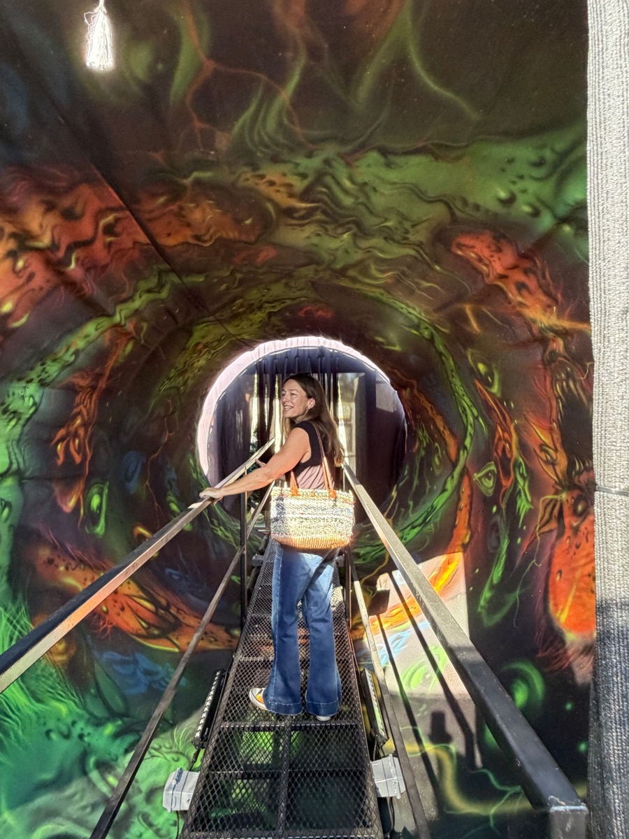 April Garner on a metal walkway through a swirling, painted tunnel inside the haunt