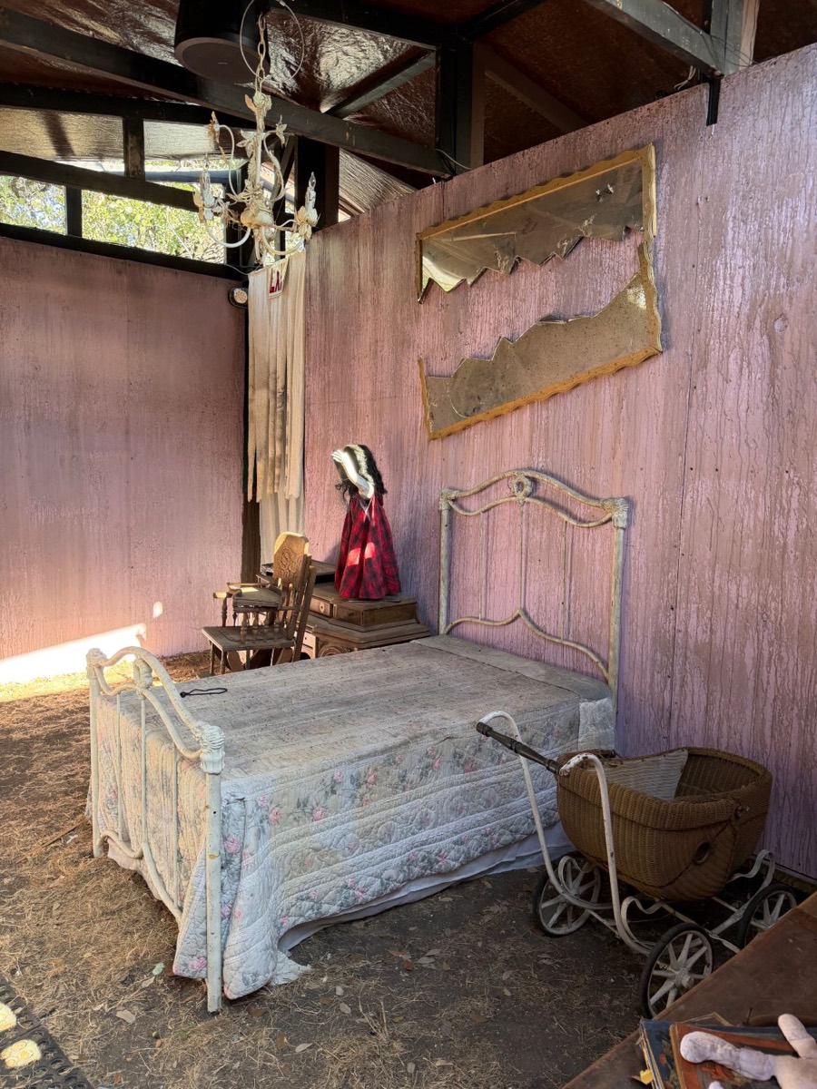 The twins' bedroom from The Well, with an iron bed, floral quilt, shattered mirrors and an antique wicker pram