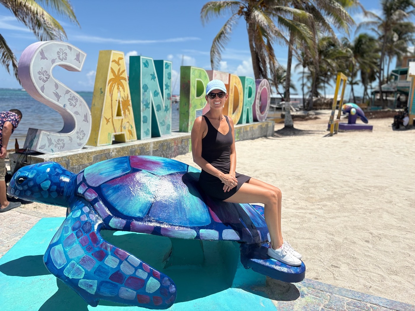 Salissa sitting on a painted sea turtle sculpture in front of the San Pedro sign in Belize