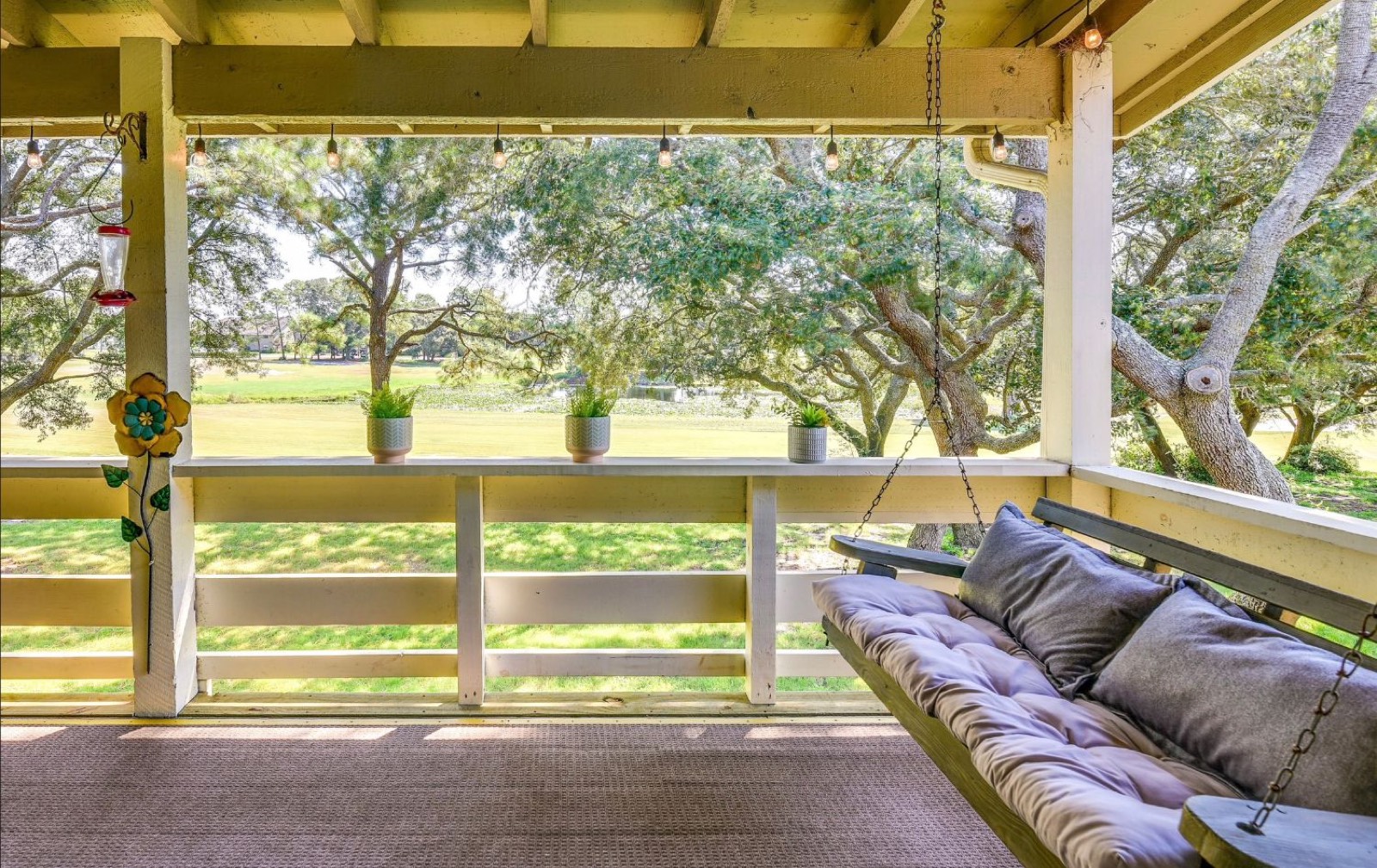 Covered porch swing overlooking live oaks and the golf course