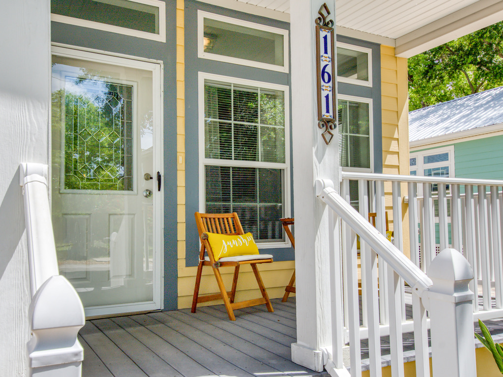 Front porch of the St. Augustine rental with a yellow 'sunshine' pillow on a wooden chair