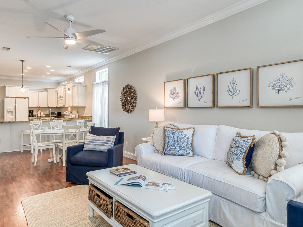 Bright living room with a white slipcovered sofa and coral prints